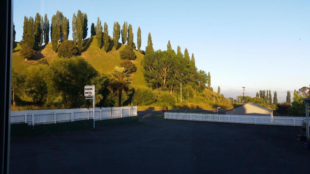une route avec une colline clôturée et des arbres dans l'établissement Mahoe Motel, à Taumarunui