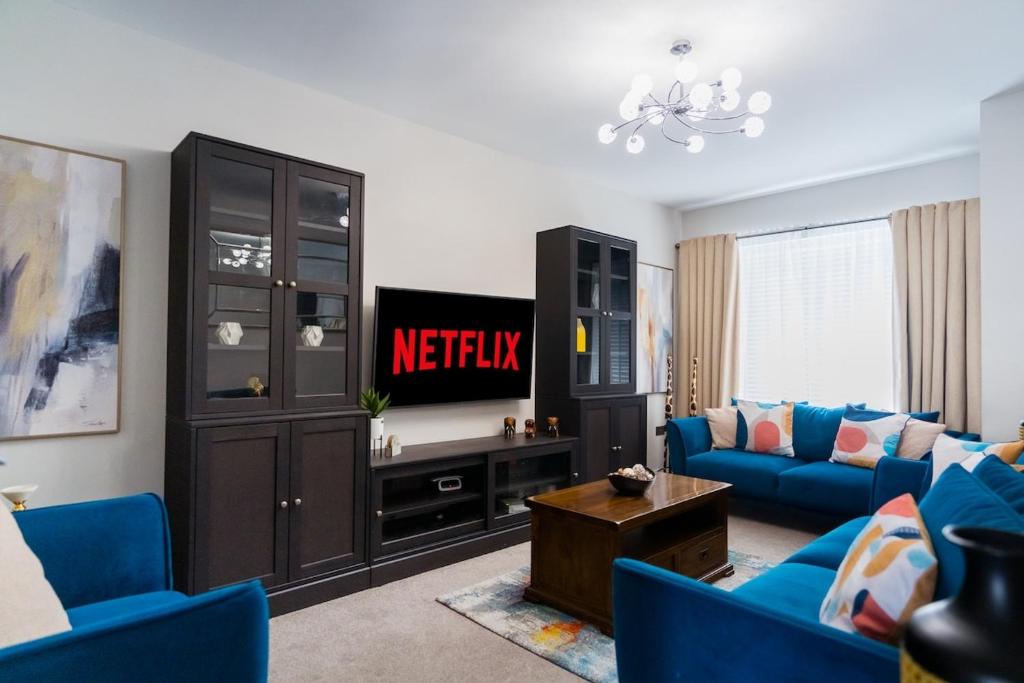 a living room with a blue couch and a tv at Dublin Premier Oasis in Ráth Cúil