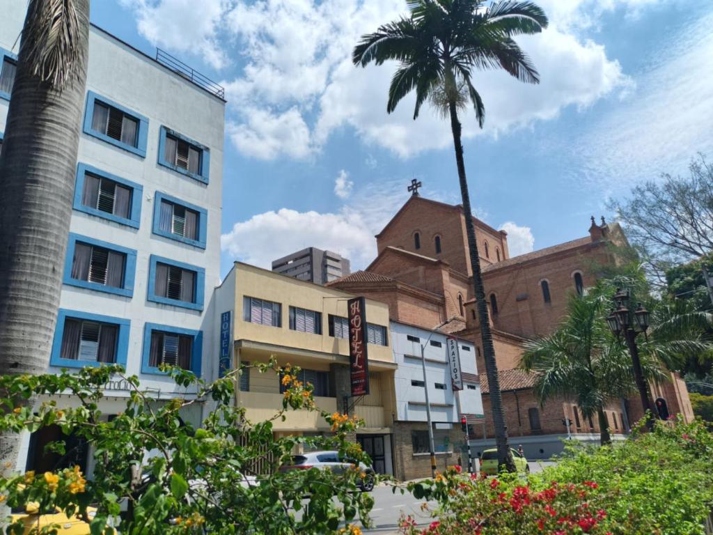 a palm tree in front of a building with a church at Hotel Villa Nueva Comfort in Medellín