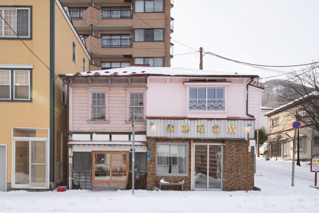 a building on a street with snow on the ground at 佐藤理容Inn in Hakodate