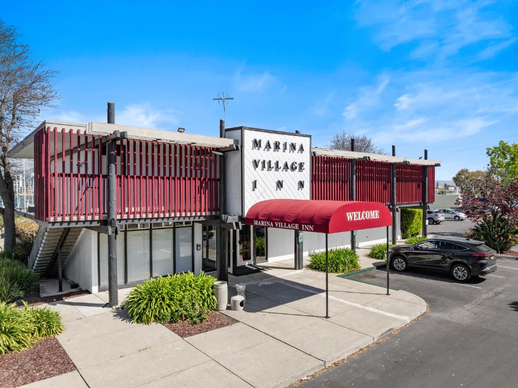 a building with a red awning in a parking lot at Marina Village Inn in Alameda