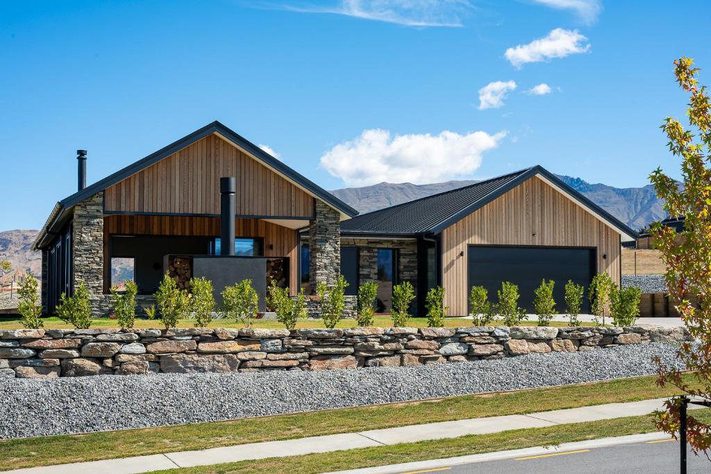 a home with a stone retaining wall in front of a house at Carrickmore Lodge in Wanaka