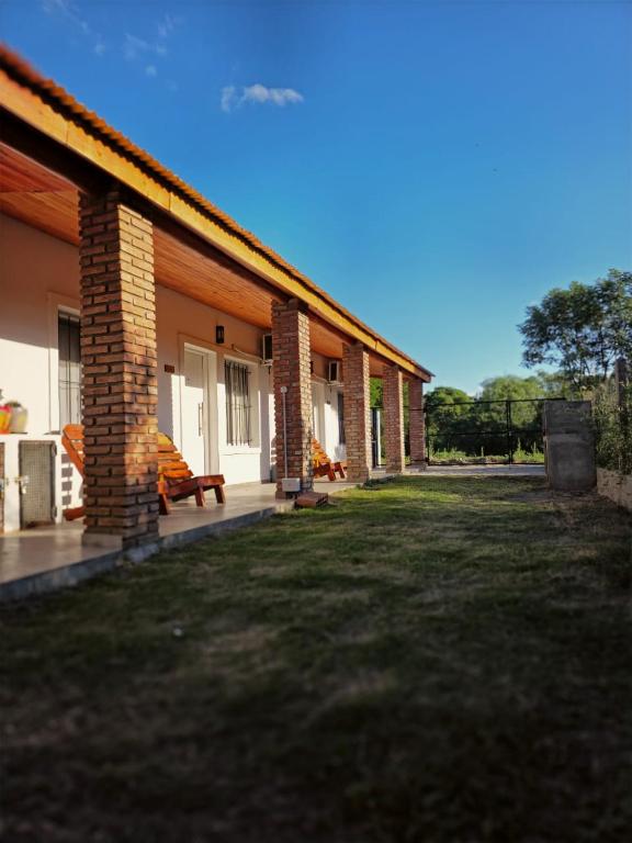 a house with a grass yard next to a building at Departamentos Los Árboles in San Francisco del Monte de Oro