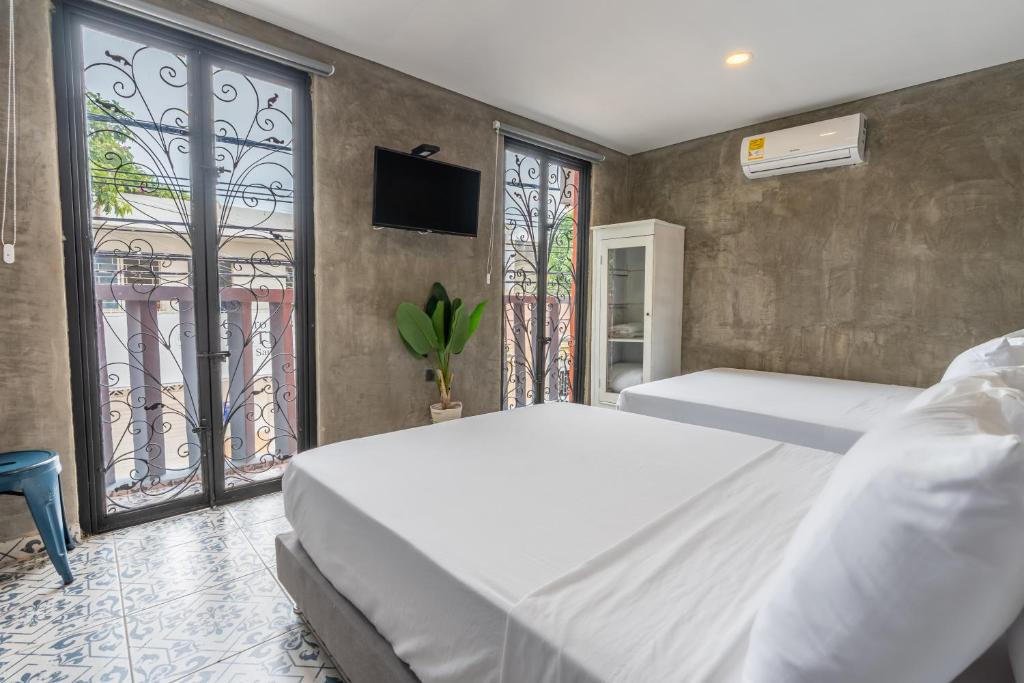 a bedroom with two beds and a tv and windows at Casa Presentacion Adaz Hotel in Santa Marta