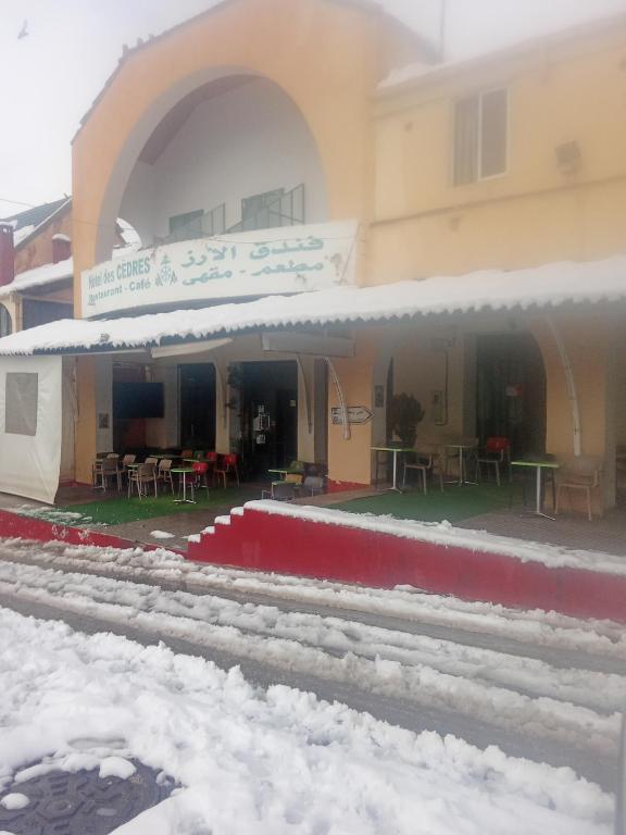 a train station in the snow with tables and chairs at Hôtel des cedresazrou in Azrou