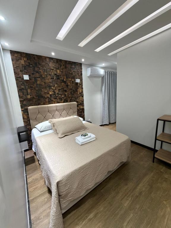a bedroom with a bed and a brick wall at POUSADA CITRINO in Ametista do Sul