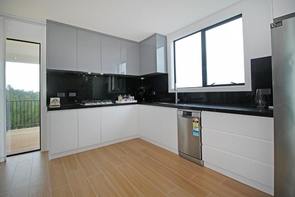 a kitchen with white cabinets and a wooden floor at Your Private Escape with city views in Auckland