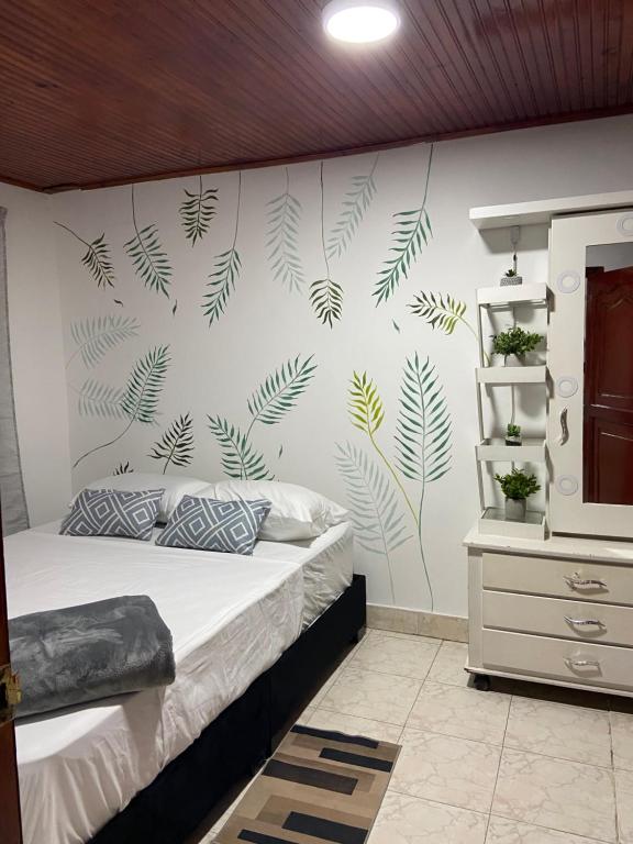 a bedroom with a bed with green leaves on the wall at Hostal Amelia Filandia in Filandia