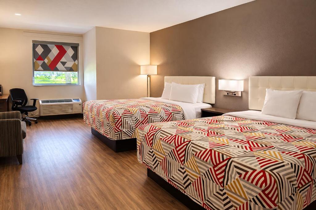 a hotel room with two beds and a desk at Motel 6 Lake City, FL – Medical Center in Lake City