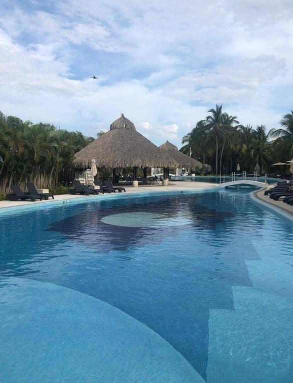 a large swimming pool with a thatched resort at Villa en Terrasol Diamante in Acapulco