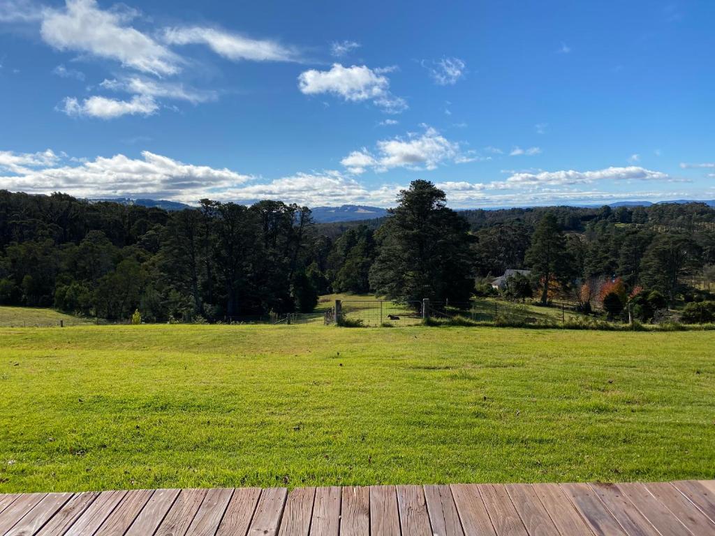 a wooden deck with a field of green grass at Mirradong Cottage in Berambing