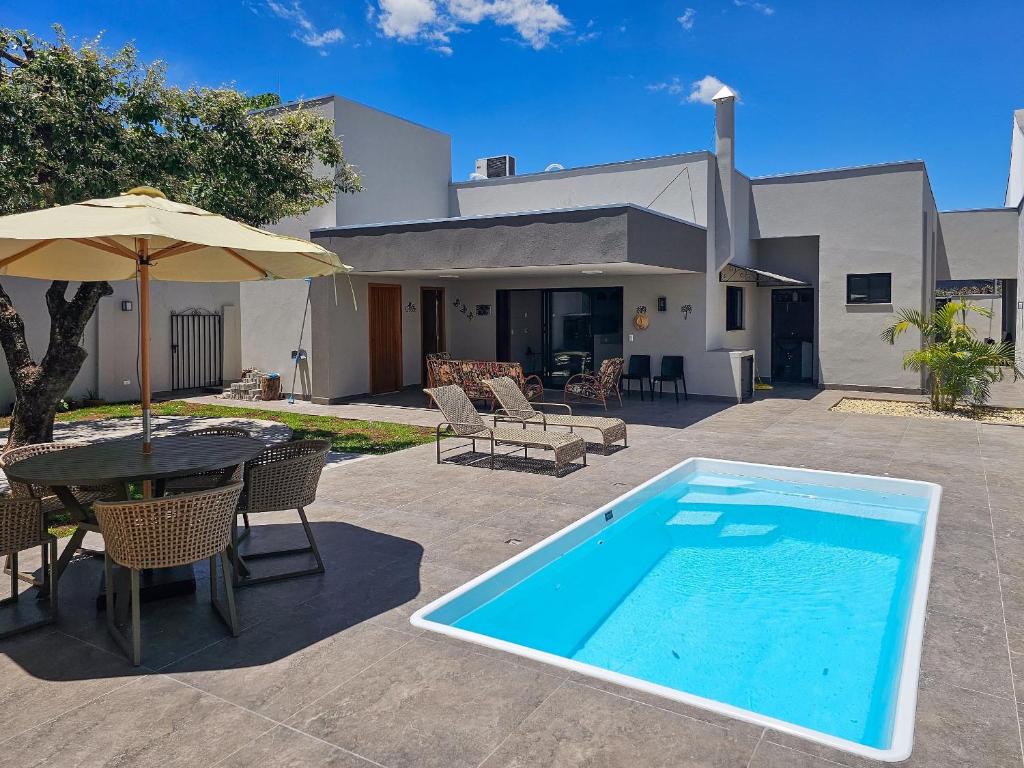 a swimming pool with a table and an umbrella at Casa Ninhal, super central, nova e espaçosa. in Bonito
