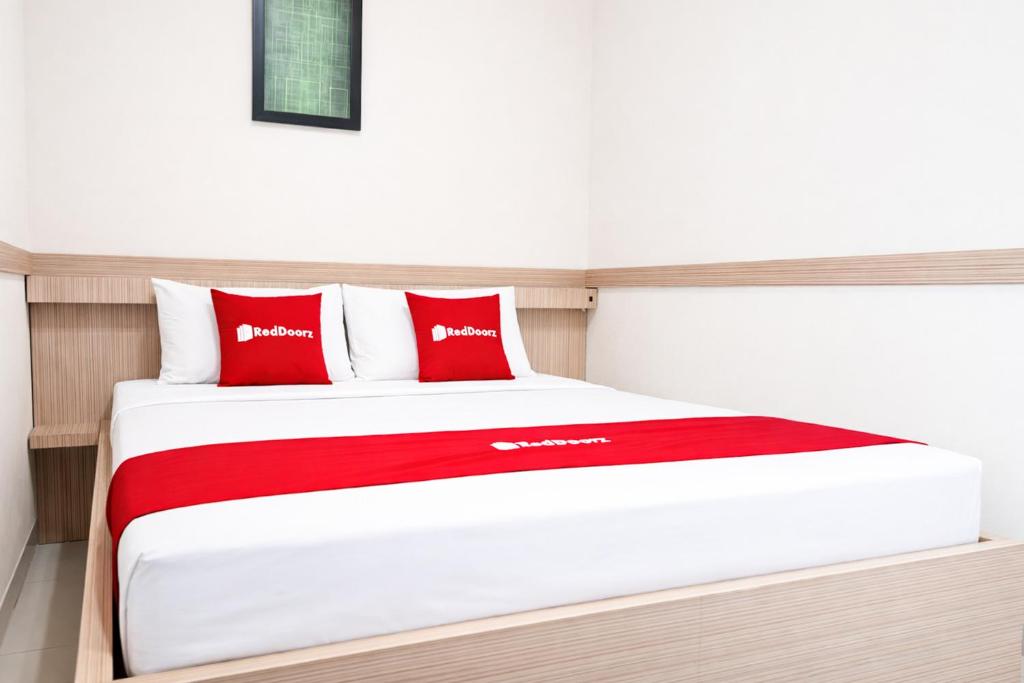a bed in a room with red and white pillows at RedDoorz Plus near The Great Asia Africa Lembang in Bandung
