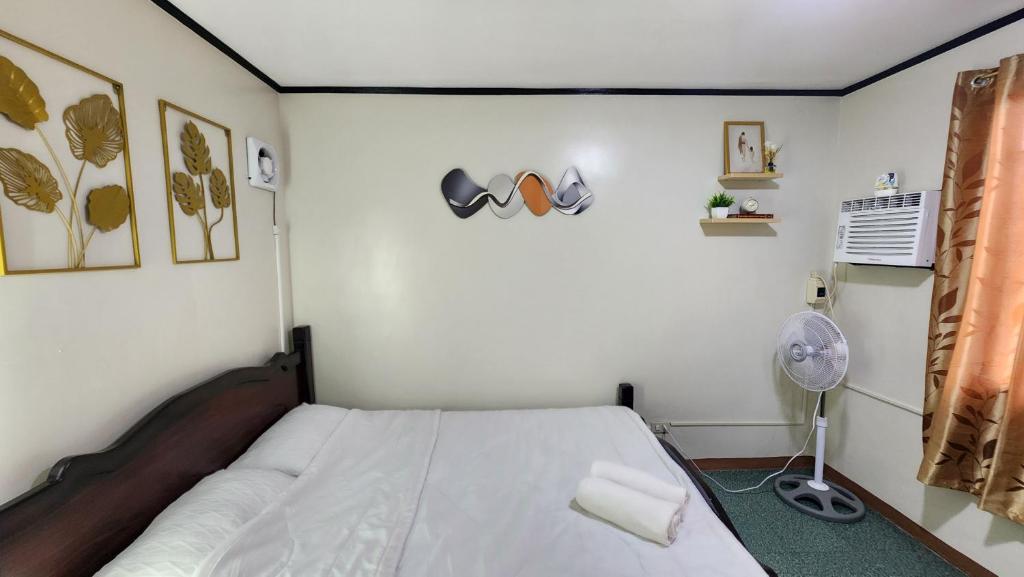 a bedroom with a white bed and a fan at Raed Homestay by ASH in Biñan