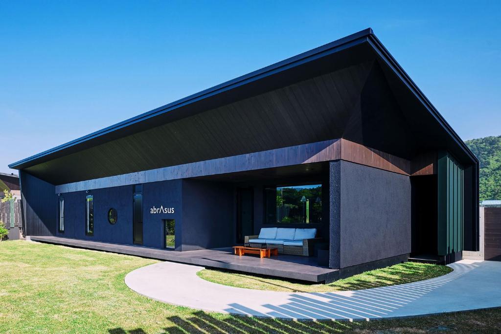 a black house with a bench in a yard at abrAsus house Fuji in Narusawa