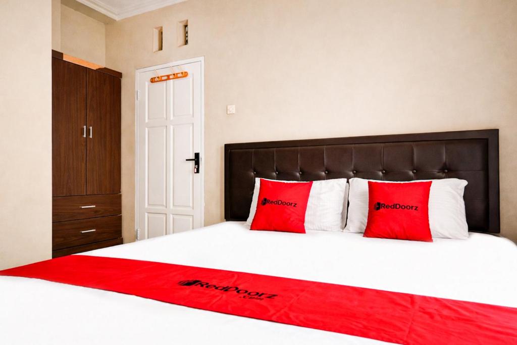 a bedroom with a large bed with two red pillows at RedDoorz Syariah at Cimahi in Cimindi
