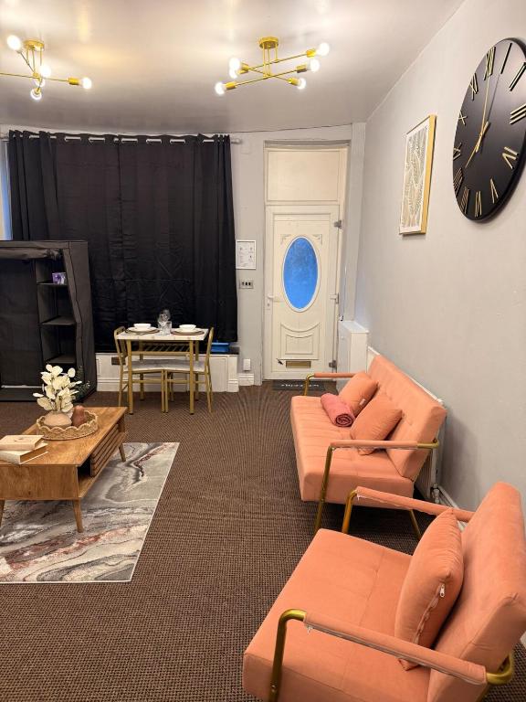 a living room with orange furniture and a clock on the wall at Studio Aurelia - Oldham city centre in Oldham