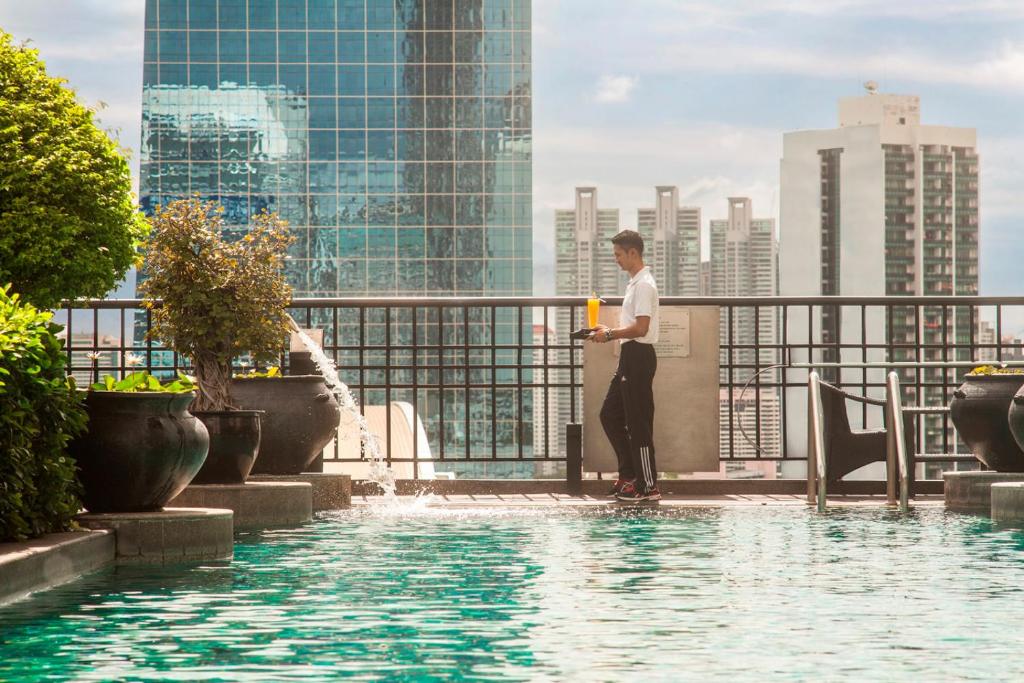 A rooftop pool with city views and a server beside the water.