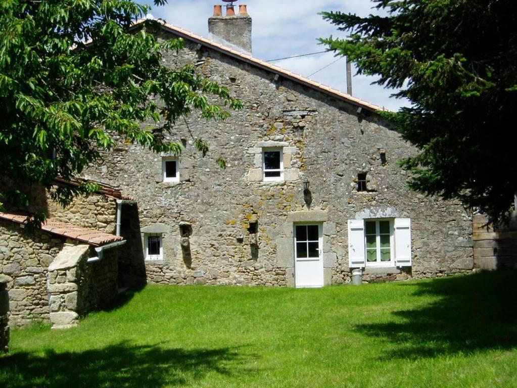 an old stone house with green grass in front of it at Les bonnes fontaines in Cieux