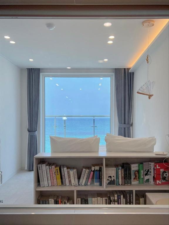 a bedroom with a large window with a book shelf at Mr. Slow in Sokcho