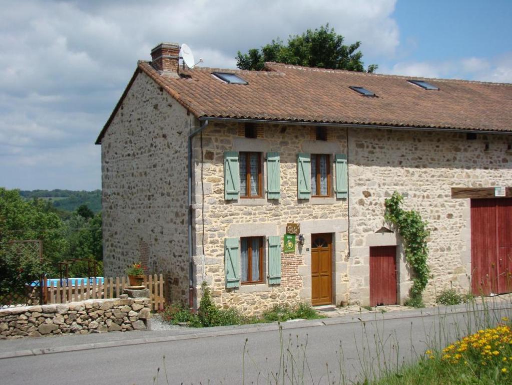 a stone house with a red door on a street at Le bourg in Vaulry
