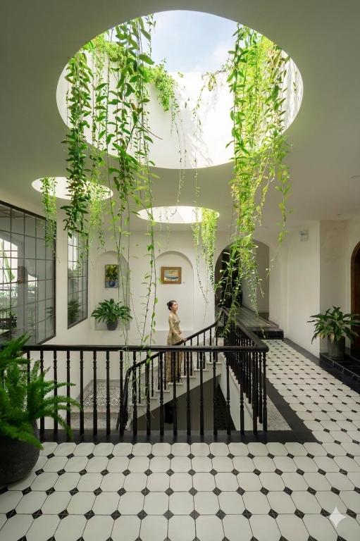 a person walking down a staircase in a building with plants at Paul Chabot Hotel in Hai Phong