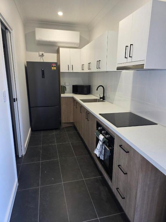 a kitchen with white cabinets and a black refrigerator at Heritage City Motor Inn in Broken Hill