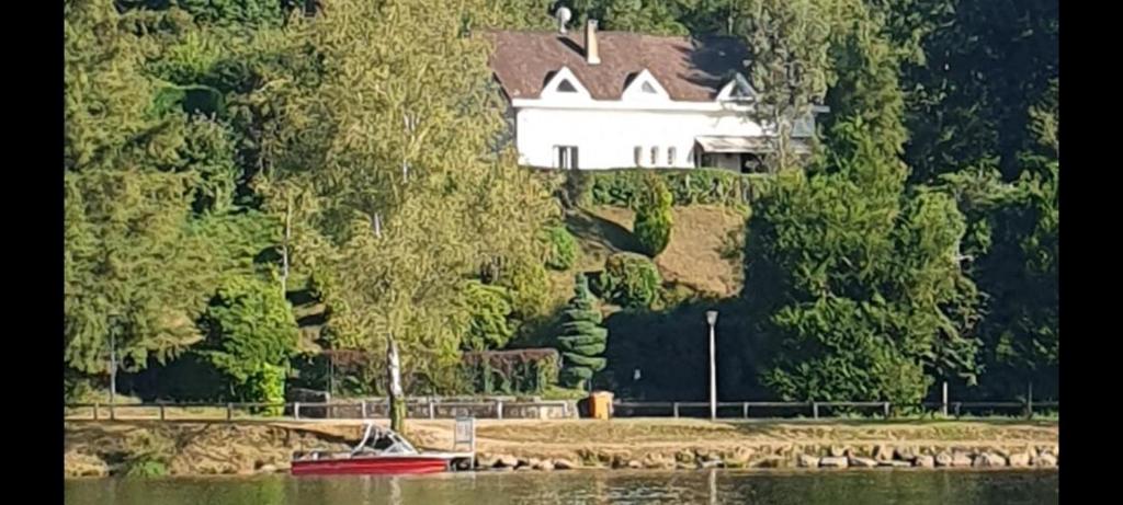 a house on a hill with a boat in the water at Villa du lac in Bujaleuf
