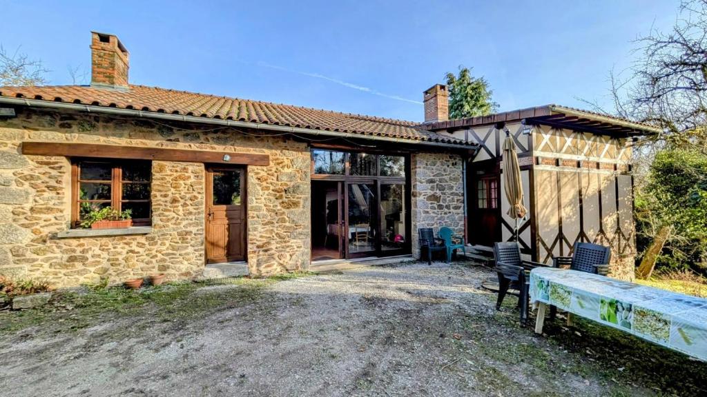 a small stone house with a bench in front of it at Les landes in Champnétery