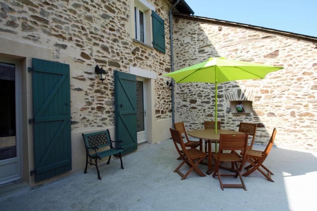 a table and chairs with a green umbrella on a patio at La petite ecosse in Châteauneuf-la-Forêt