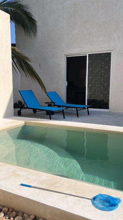 two blue lounge chairs sitting next to a swimming pool at La Belle Dojo in Chelem