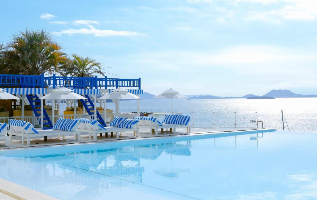 a swimming pool with blue and white chairs and the water at Latterace Resort in Yeosu