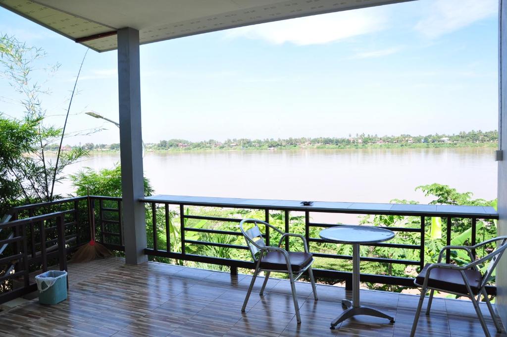 a balcony with chairs and a table and a view of a river at The Rim Riverside Guest House in Nong Khai