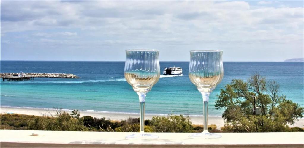 two wine glasses sitting on a table near the beach at Penneshaw Beach House in Penneshaw