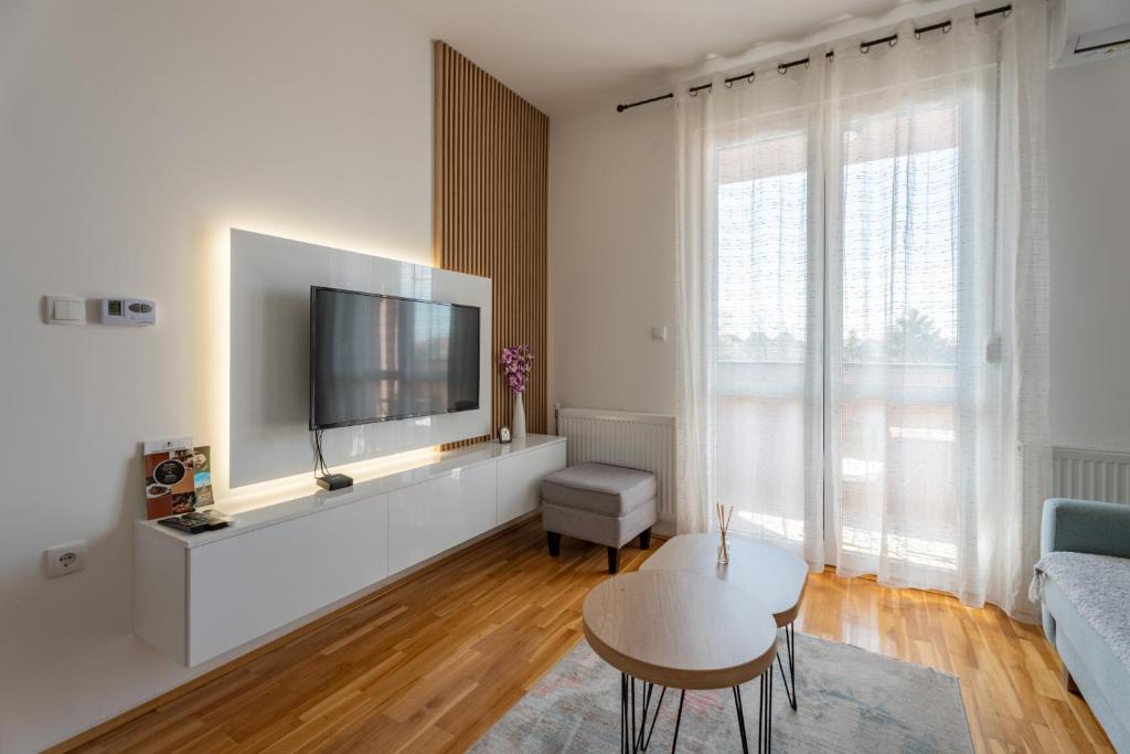 a living room with a flat screen tv on a wall at HM Apartments in Inđija