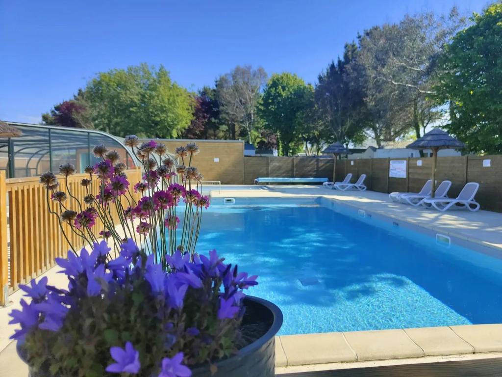 a swimming pool with flowers in a vase next to it at Camping 3 étoiles - Piscine - à 2 minutes des plages in Penvénan