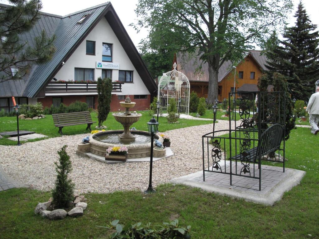 a garden with a fountain in front of a house at Wellness hotel Harrachovka in Harrachov