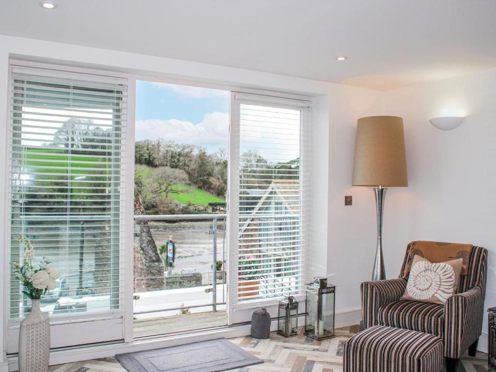a living room with a large window and a chair at Estuary View in Kingsbridge