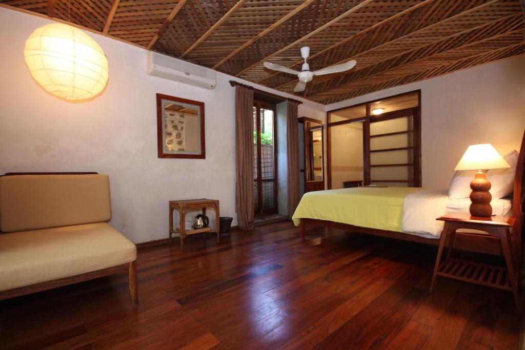 a bedroom with a bed and a couch and a fan at Sala Prabang Hotel in Luang Prabang