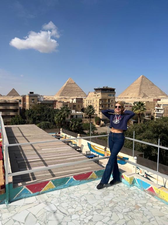 a woman standing on top of a building with pyramids at Matto Pyramids Inn in Cairo