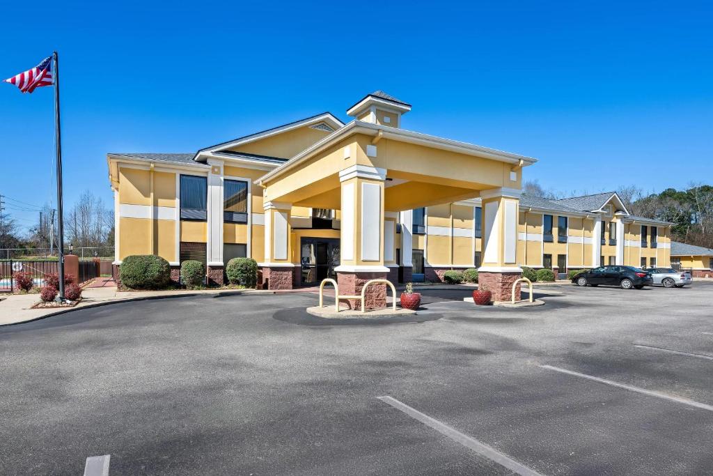 a large yellow building with a flag in a parking lot at Quality Inn Alexander City in Alexander City