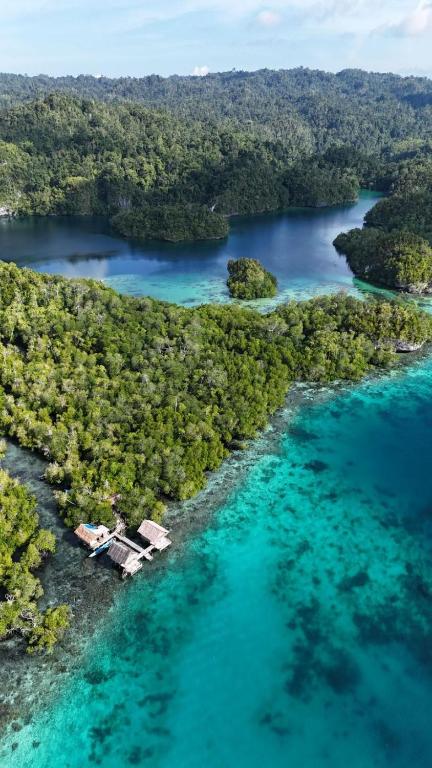 an aerial view of a tropical island with turquoise water at Sunrise Raja Ampat in Besir