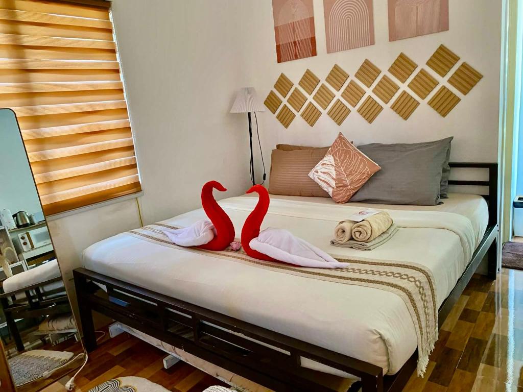 two red swans sitting on a bed in a bedroom at Olango Island-Tiny Guest House Fully Furnished with Hot Shower, Washer, Wi-Fi, Netflix & King Bed S&E-3 in Lapu Lapu City