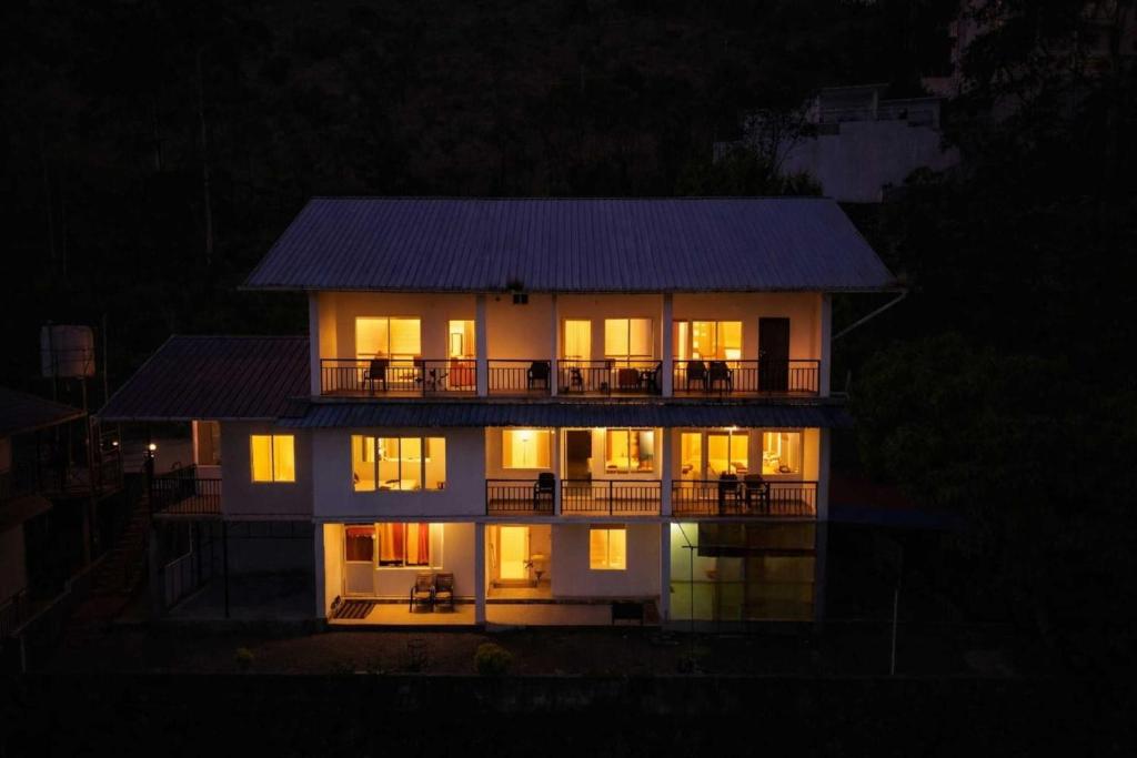 a large house with its lights on at night at Rock And Mist Munnar House Resort in Munnar