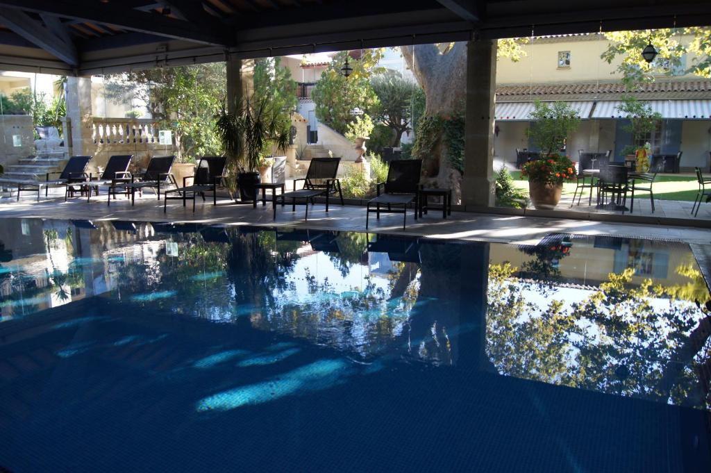 una piscina con sillas, una mesa y un edificio en La Villa Mazarin, en Aigues-Mortes