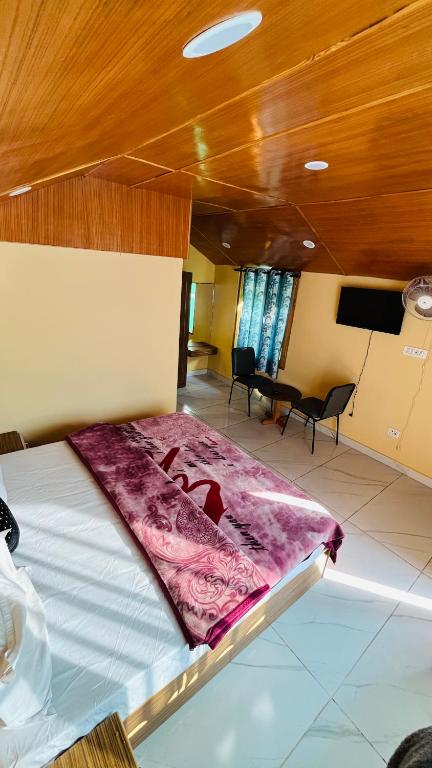 a bed in a room with a flat screen tv at Mahi camping & cottages in Jagatsukh