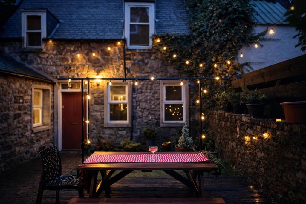 a wooden table in front of a house with lights at Secret City Cottage - Peaceful - Private Garden in Aberdeen