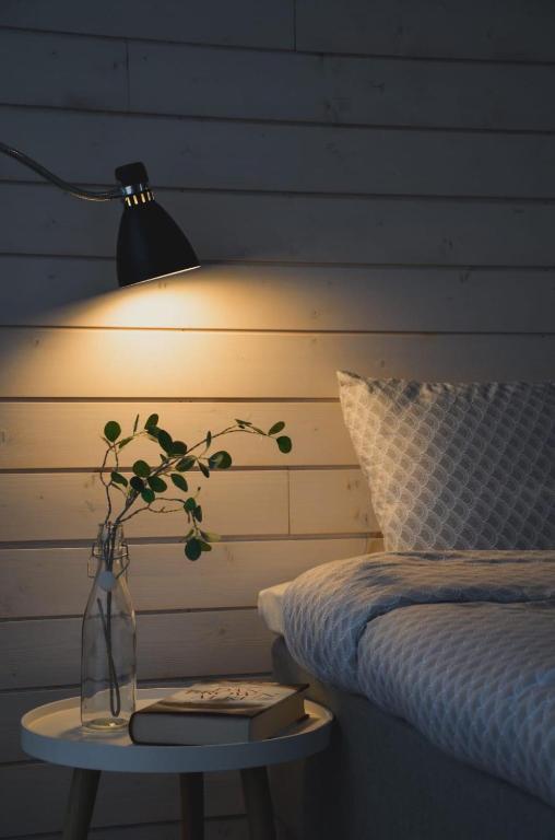 a lamp and a table with a vase on a bed at Willa Rauha E, minikoti saunalla, iso parkkialue in Lumijoki
