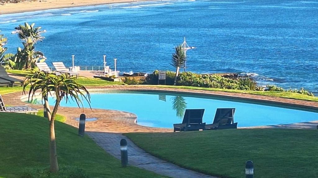 a swimming pool with two chairs next to the ocean at 130 Brookes Hill Suites in Port Elizabeth