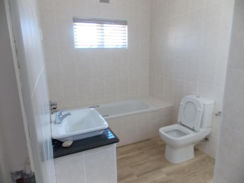 a white bathroom with a sink and a toilet at Burd's Nest 215 in Shelly Beach